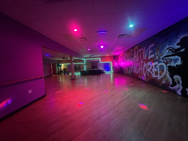 The Active + Anchored dance floor lit in neon pink and cyan, ready for class